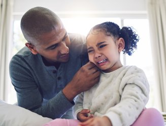 Une enfant qui pleure et consolé par son parent